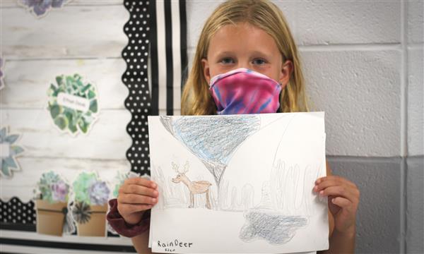 student holds up drawing